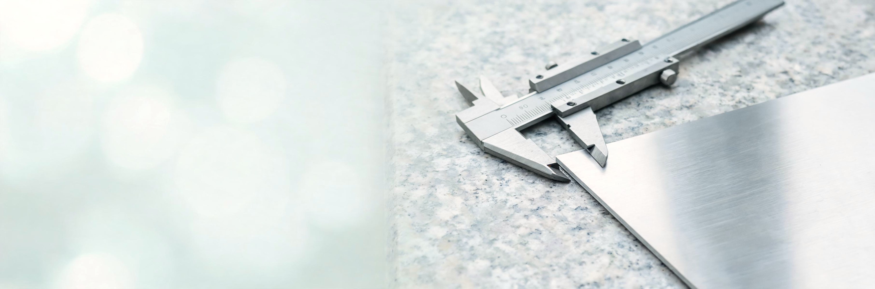Vernier caliper on a metal work surface for component measurement.